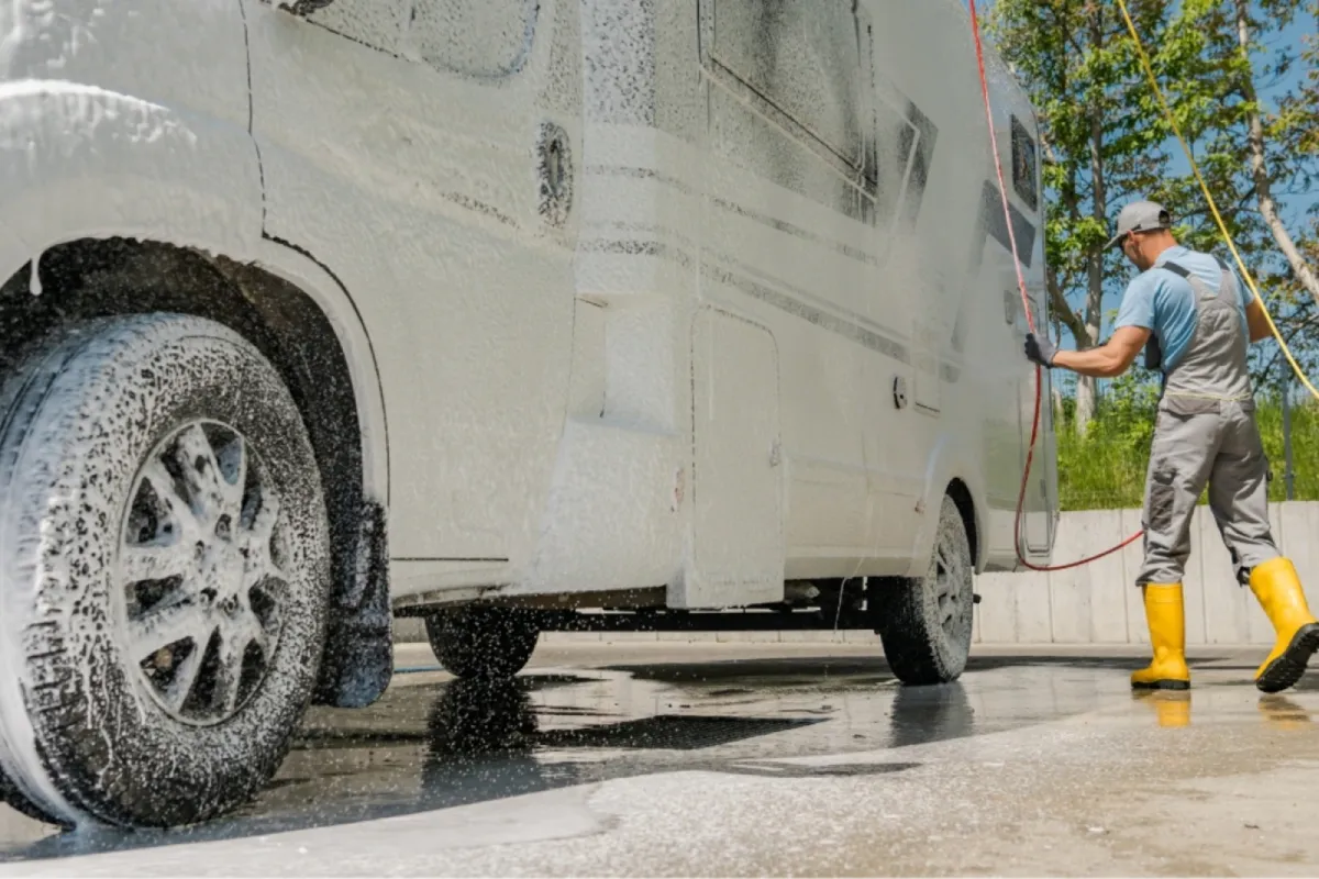 Technician washing an RV exterior with foam during RV detailing.