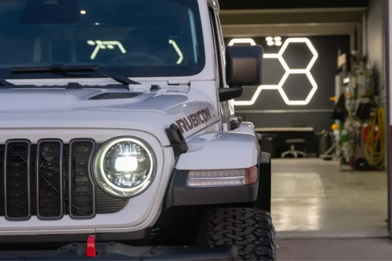 White Jeep Rubicon parked inside a garage workshop preparing for window tinting
